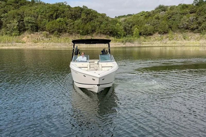 Slide: The Image of 2018 Cobalt R5 WSS Surf boat cruising on a serene lake with lush green surroundings. - 19