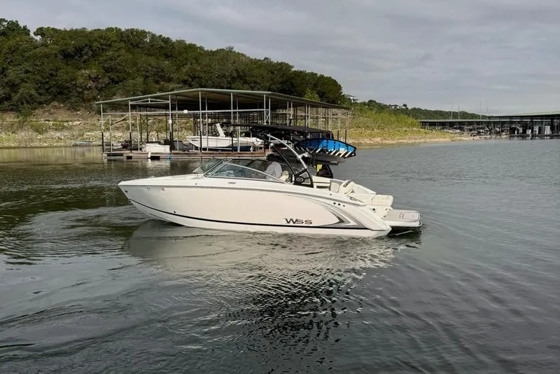 Slide: The Image of 2018 Cobalt R5 WSS Surf boat cruising on a calm lake near a marina. - 7