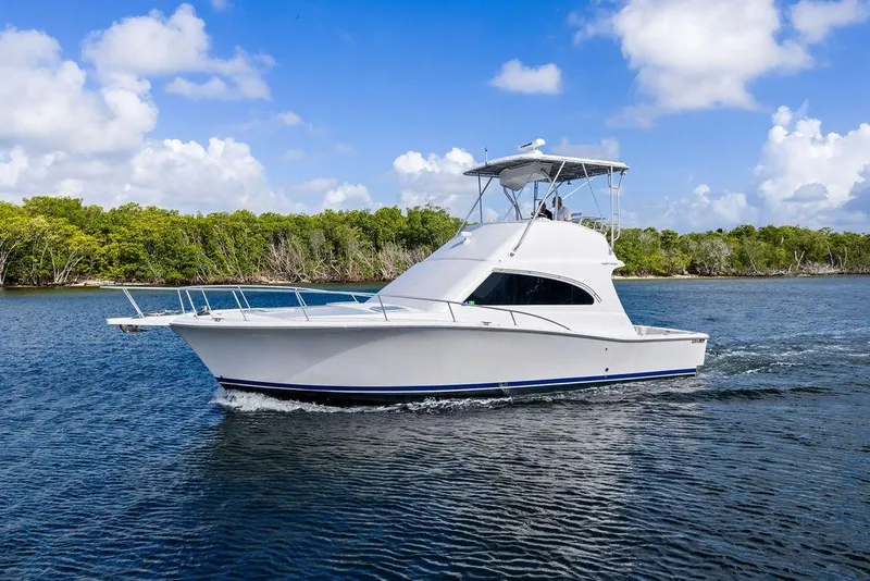 Slide: The Image of 2005 Luhrs 38 Convertible yacht cruising on a serene waterway under a clear blue sky. - 12