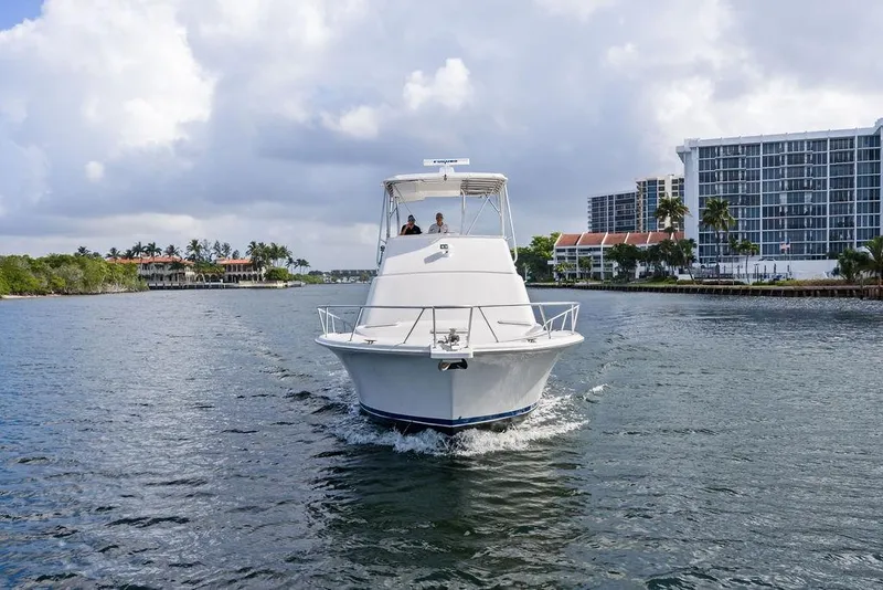 Slide: The Image of 2005 Luhrs 38 Convertible yacht cruising near waterfront buildings under cloudy skies. - 13