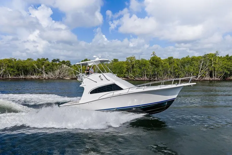 Slide: The Image of 2005 Luhrs 38 Convertible yacht cruising on a scenic waterway with lush greenery. - 15