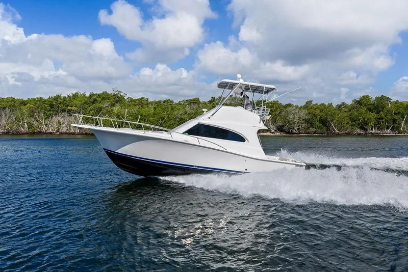Slide: The Image of 2005 Luhrs 38 Convertible yacht cruising on a scenic waterway under a partly cloudy sky. - 19