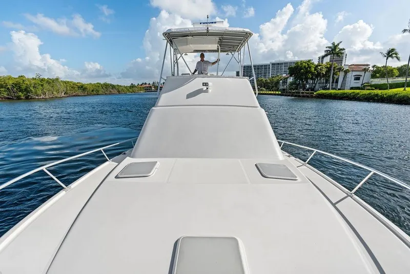 Slide: The Image of 2005 Luhrs 38 Convertible yacht cruising on a scenic waterway under a clear blue sky. - 31