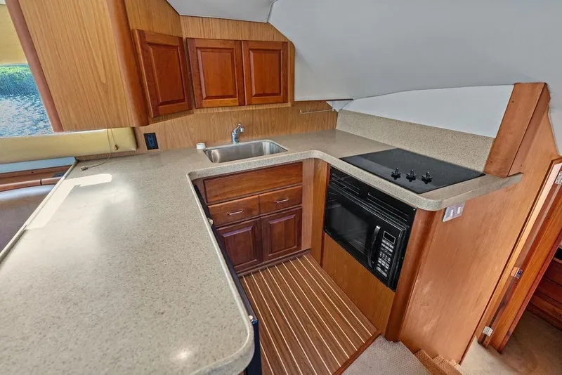 Slide: The Image of 2005 Luhrs 38 Convertible yacht kitchen with wooden cabinets and modern appliances. - 34