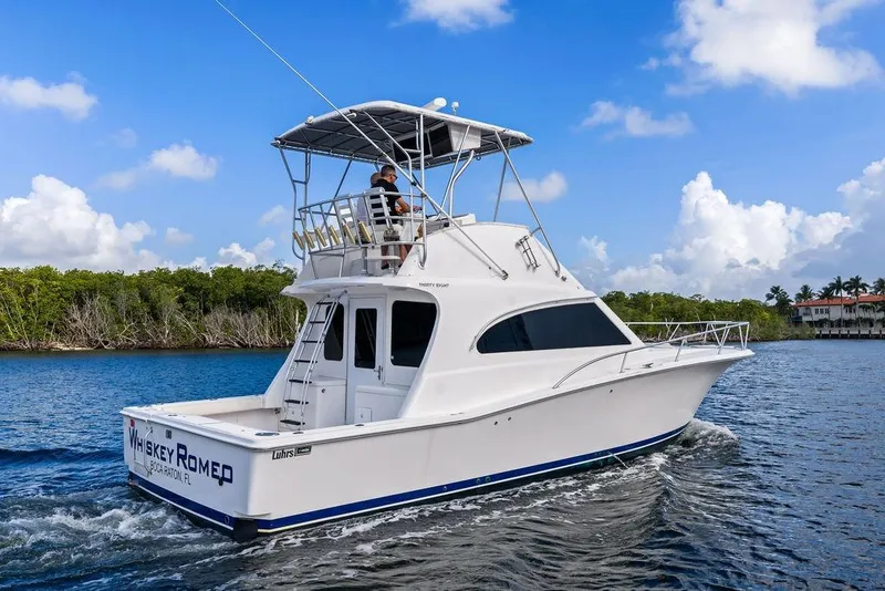 Slide: The Image of 2005 Luhrs 38 Convertible yacht cruising on a sunny day, with lush greenery in the background. - 4
