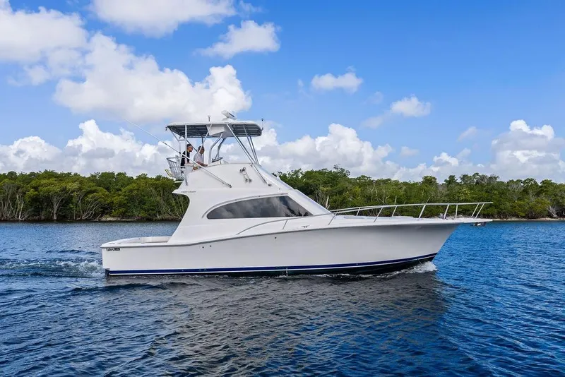 Slide: The Image of 2005 Luhrs 38 Convertible yacht cruising on a serene blue lake under a clear sky. - 5