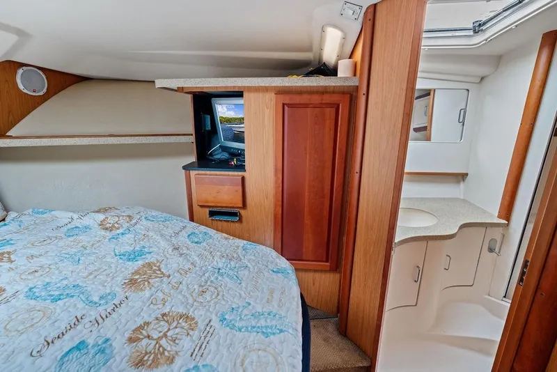Slide: The Image of 2005 Luhrs 38 Convertible cabin interior with bed, TV, and bathroom vanity. - 55