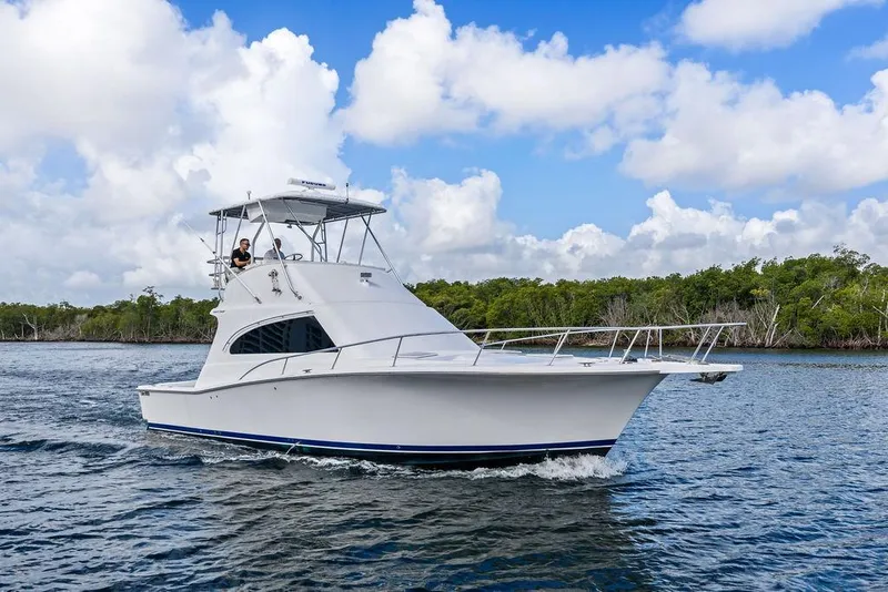 Slide: The Image of 2005 Luhrs 38 Convertible yacht cruising on a scenic waterway under a blue sky. - 6