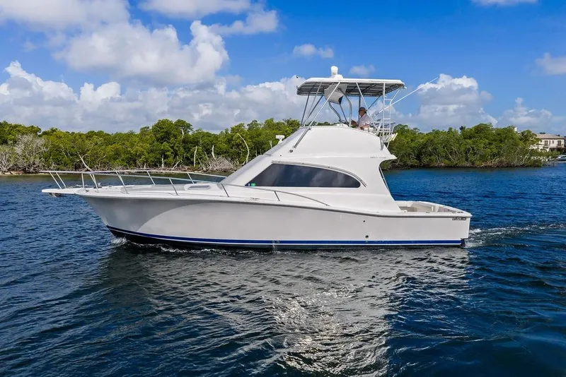 Slide: The Image of 2005 Luhrs 38 Convertible yacht cruising on a sunny day, surrounded by lush greenery. - 9