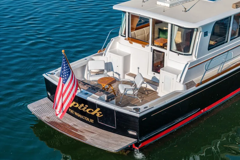 Slide: The Image of 2008 Grand Banks 45 Eastbay SX yacht with American flag, docked in calm waters. - 3