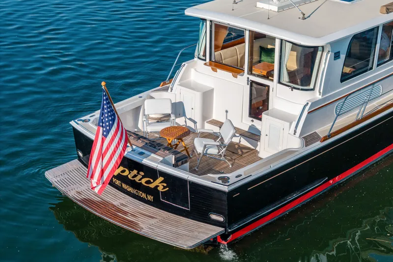Slide: The Image of 2008 Grand Banks 45 Eastbay SX yacht with American flag, docked in calm water. - 5