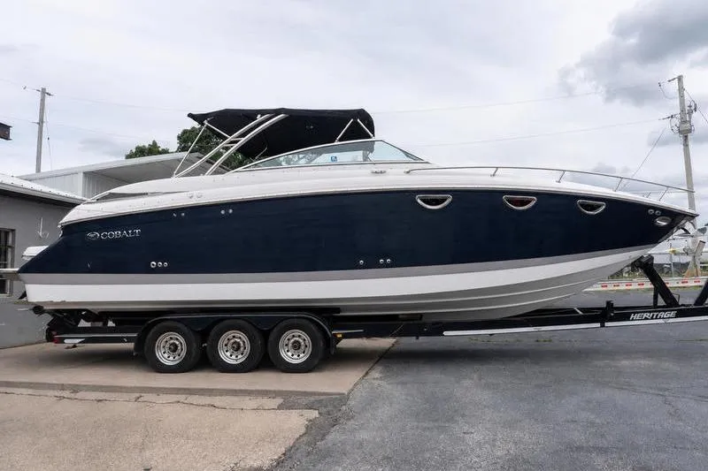 The Image of 2007 Cobalt 323 boat on trailer, featuring sleek design and dark blue hull. - 1