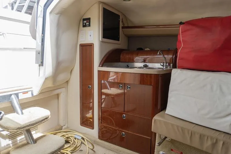 Slide: The Image of Interior of a 2007 Cobalt 323 boat featuring a compact kitchenette and seating area. - 19