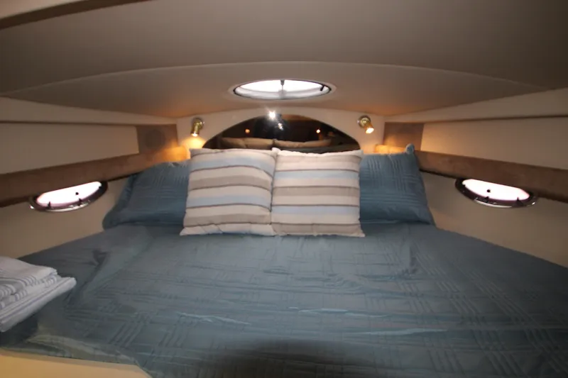 Slide: The Image of Cozy cabin interior of 2003 Cruisers Yachts 320 Express with blue bedding and porthole windows. - 18