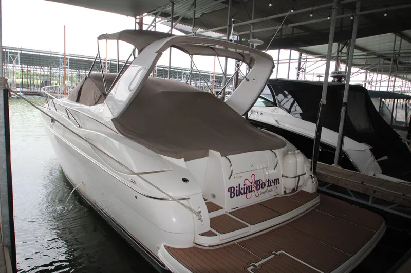 Slide: The Image of 2003 Cruisers Yachts 320 Express docked in marina, covered with brown canvas. - 2