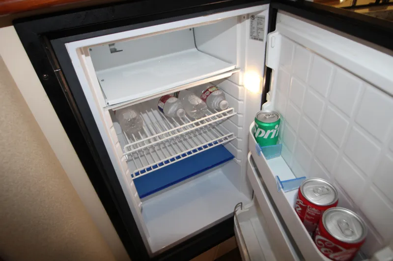Slide: The Image of Mini fridge inside 2003 Cruisers Yachts 320 Express, stocked with drinks and water bottles. - 25
