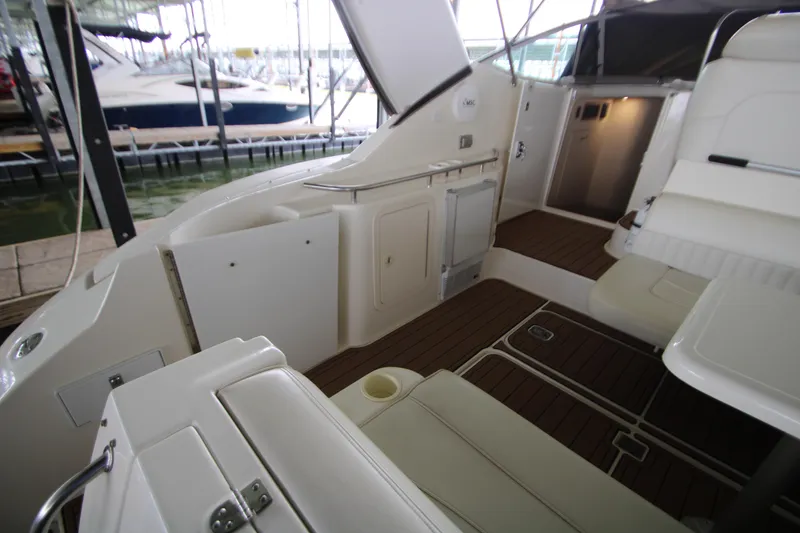 Slide: The Image of 2003 Cruisers Yachts 320 Express interior with seating and wood flooring in a marina setting. - 7