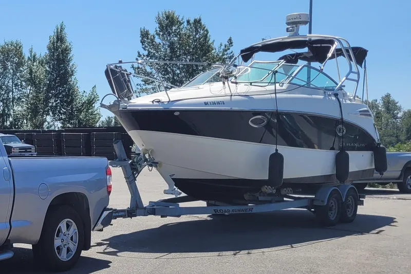 Slide: The Image of 2008 Maxum 2700 SE boat on trailer, hitched to a silver truck in a parking lot. - 2