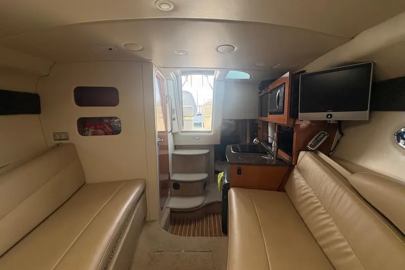 Slide: The Image of 2008 Maxum 2700 SE cabin interior with beige seating, kitchenette, and TV. - 33