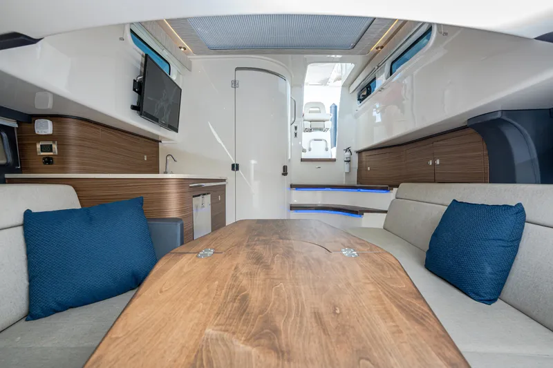 Slide: The Image of Interior of 2019 Boston Whaler 420 Outrage with modern seating and wooden table. - 12