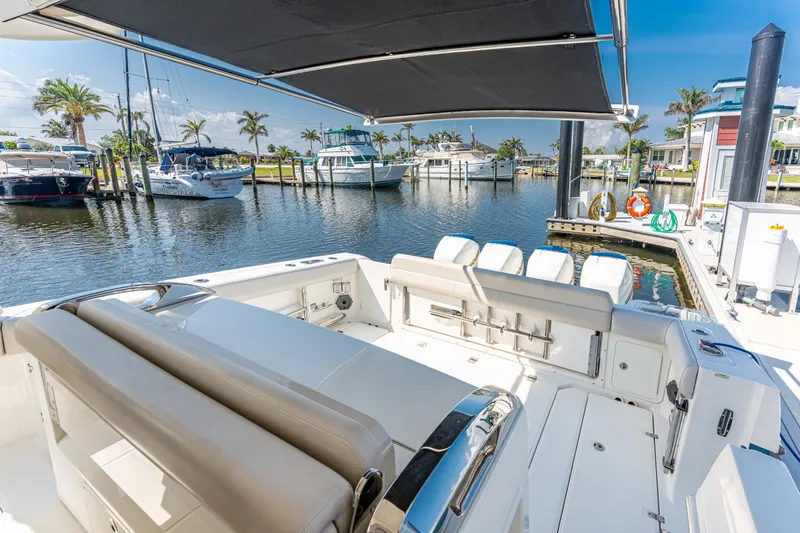 Slide: The Image of 2019 Boston Whaler 420 Outrage docked, featuring spacious seating and canopy, in a sunny marina. - 23