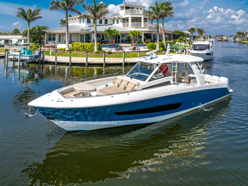 Slide: The Image of 2019 Boston Whaler 420 Outrage boat cruising near waterfront homes and palm trees. - 34