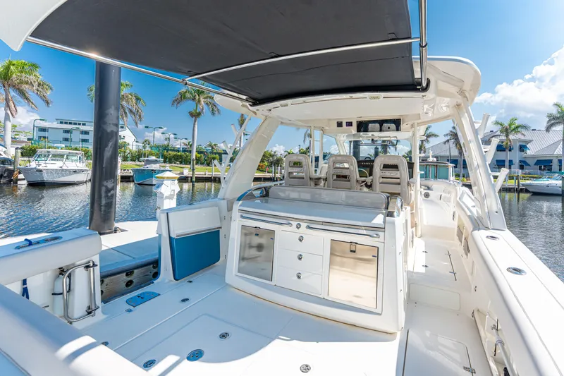 Slide: The Image of 2019 Boston Whaler 420 Outrage boat interior with seating and storage, docked in a sunny marina. - 40