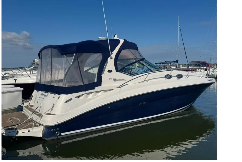 The Image of 2005 Sea Ray Sundancer 320 yacht docked in marina, featuring sleek design and blue canopy. - 0
