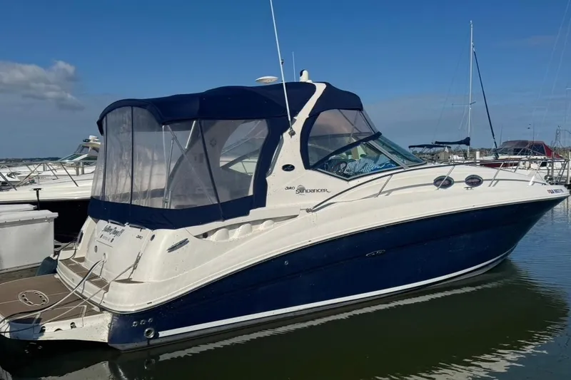 Slide: The Image of 2005 Sea Ray Sundancer 320 yacht docked in marina, featuring sleek design and blue canopy. - 2