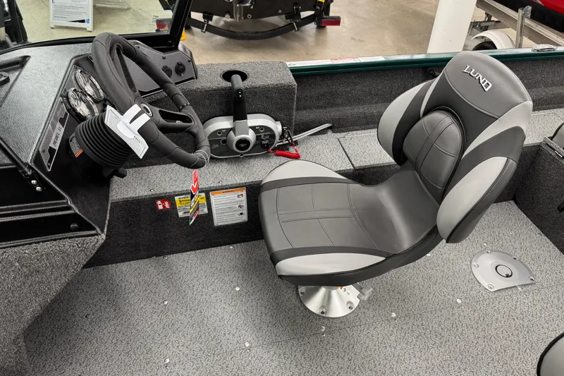 Slide: The Image of 2026 Lund 1650 Rebel XL Sport boat interior with steering wheel and cushioned seat. - 12
