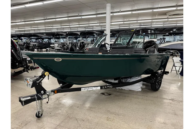 Slide: The Image of 2026 Lund 1650 Rebel XL Sport boat displayed indoors on a trailer. - 2