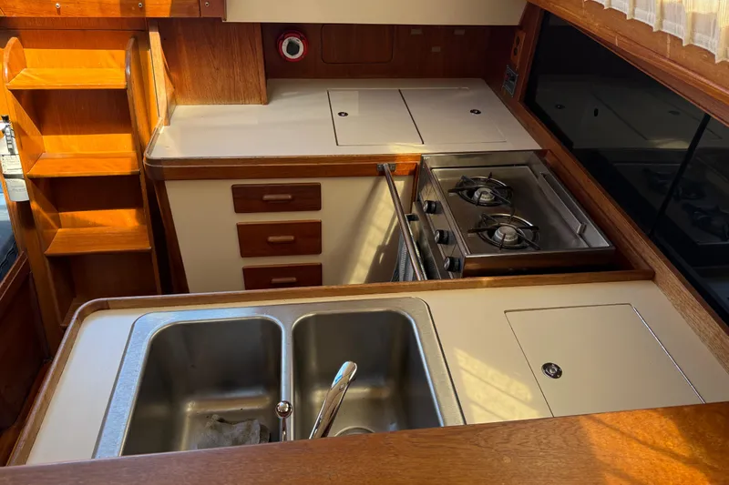 Slide: The Image of 1985 S2 11.0 meter A yacht kitchen with stove, sink, and wooden cabinetry. - 20