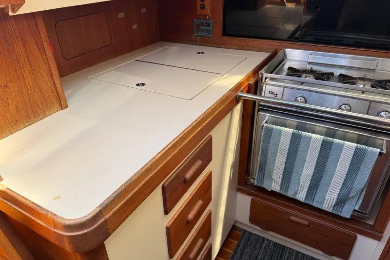 Slide: The Image of Compact 1985 S2 11.0 meter A yacht kitchen with stove, wooden cabinetry, and striped towel. - 22