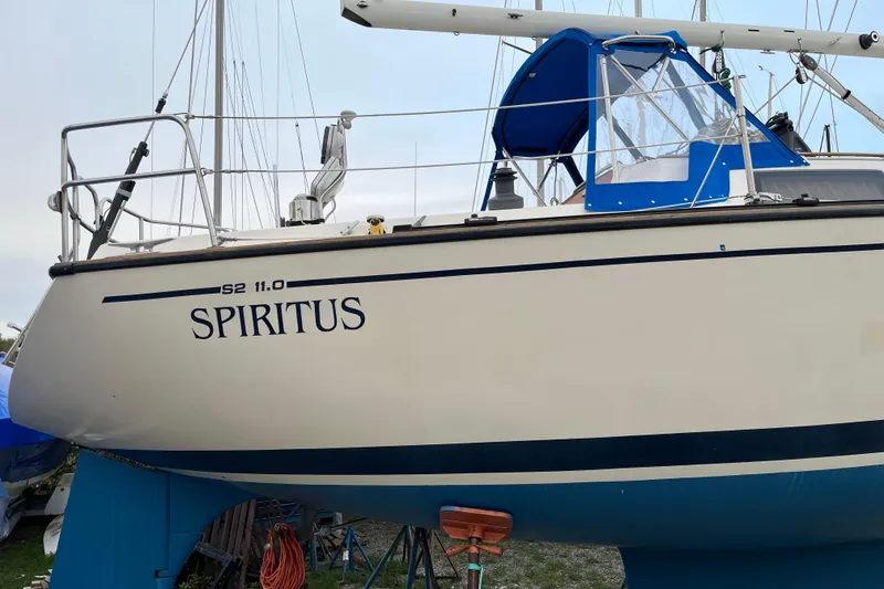 Slide: The Image of 1985 S2 11.0 meter A sailboat "Spiritus" with blue canopy, docked on land. - 35
