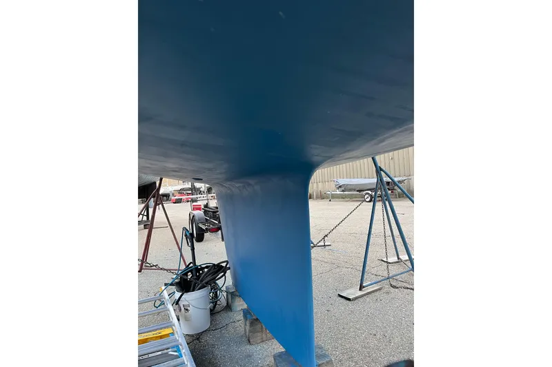 Slide: The Image of 1985 S2 11.0 meter A sailboat keel in dry dock, blue hull, marina setting. - 38
