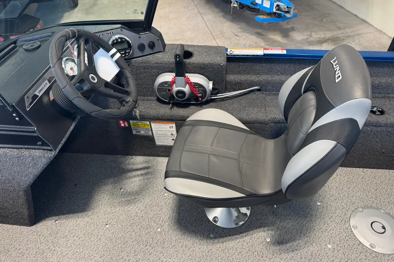 Slide: The Image of 2026 Lund 1650 Angler Sport boat interior with steering wheel and cushioned seat. - 4