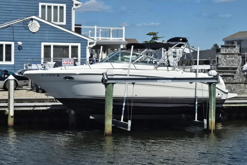 The Image of 2005 Sea Ray 290 Amberjack boat for sale, docked near a blue house. - 0