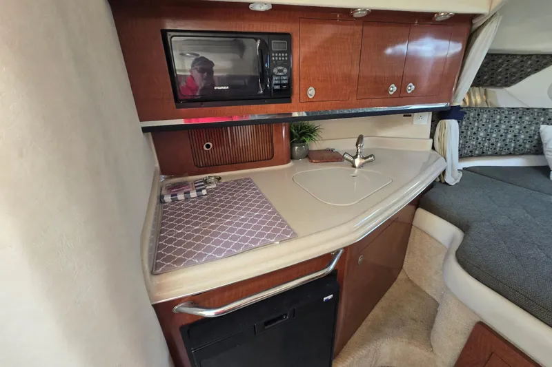 Slide: The Image of 2005 Sea Ray 290 Amberjack cabin with kitchenette, microwave, sink, and cozy sleeping area. - 16