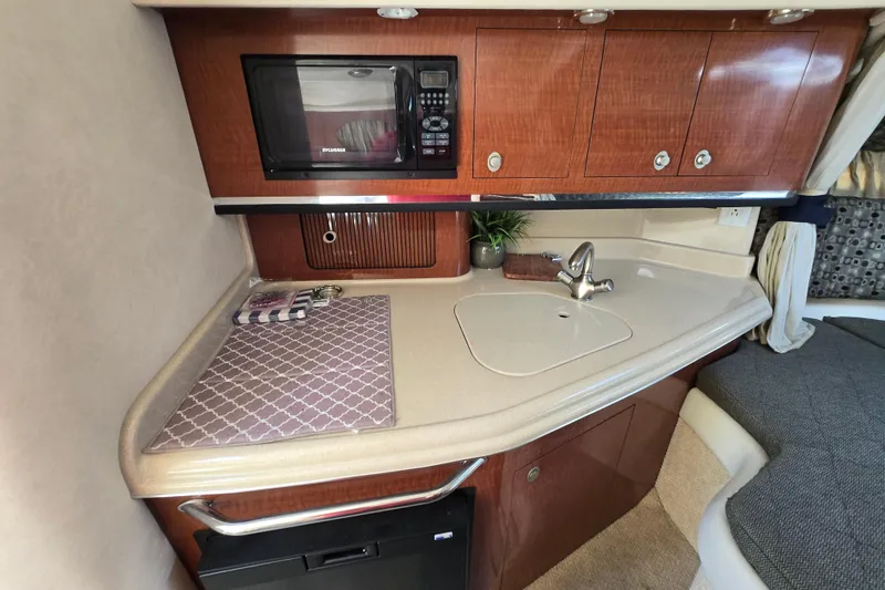 Slide: The Image of 2005 Sea Ray 290 Amberjack cabin kitchen with microwave, sink, and wooden cabinetry. - 20