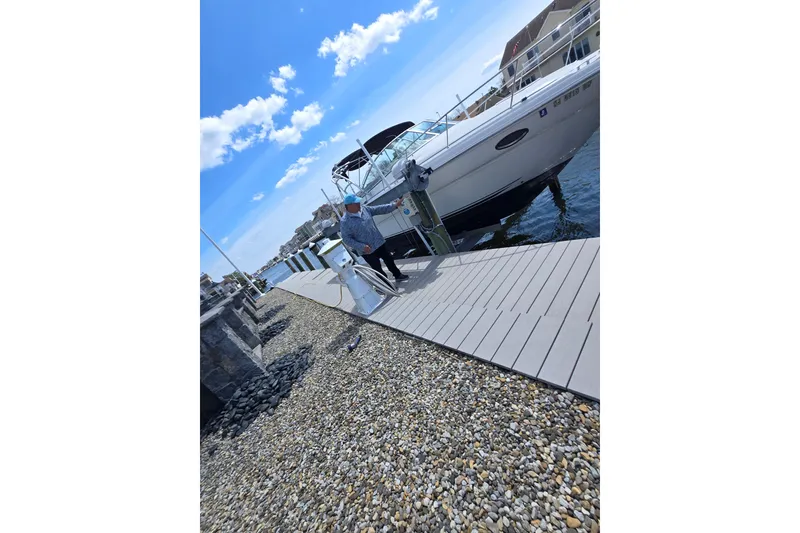 Slide: The Image of Man walking on dock beside 2005 Sea Ray 290 Amberjack boat under blue sky. - 23