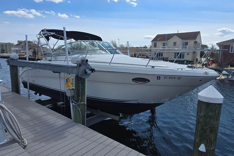 Slide: The Image of 2005 Sea Ray 290 Amberjack boat docked on a lift by waterfront homes. - 7