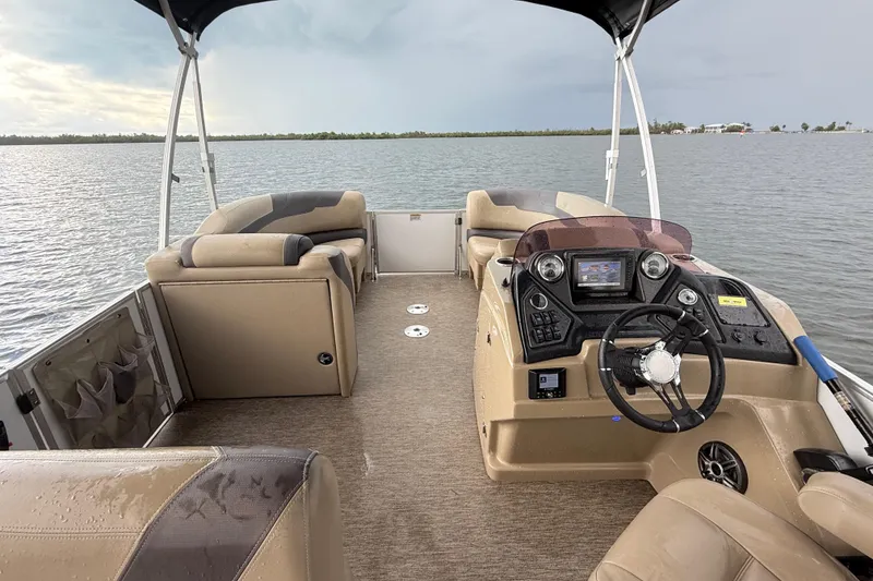 Slide: The Image of 2021 Sylvan L1 SPX pontoon boat interior with steering console on calm water. - 18