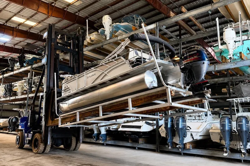 Slide: The Image of Forklift lifting a 2021 Sylvan L1 SPX pontoon boat in a storage facility. - 27