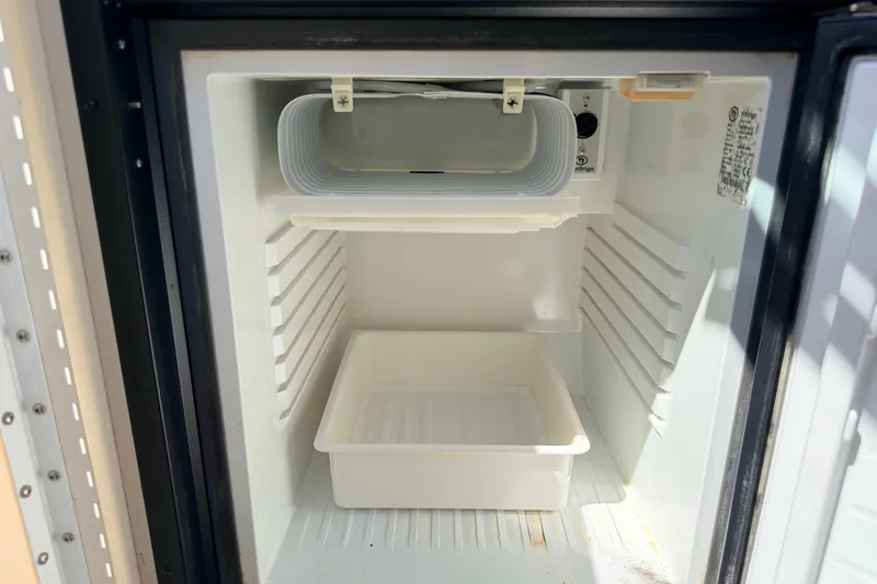 Slide: The Image of Open refrigerator inside a 2002 Formula 330 Sun Sport boat, showing empty shelves and a tray. - 39