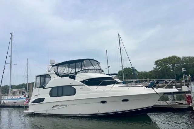The Image of 2003 Silverton 43 Motor Yacht docked at a marina under a cloudy sky. - 0