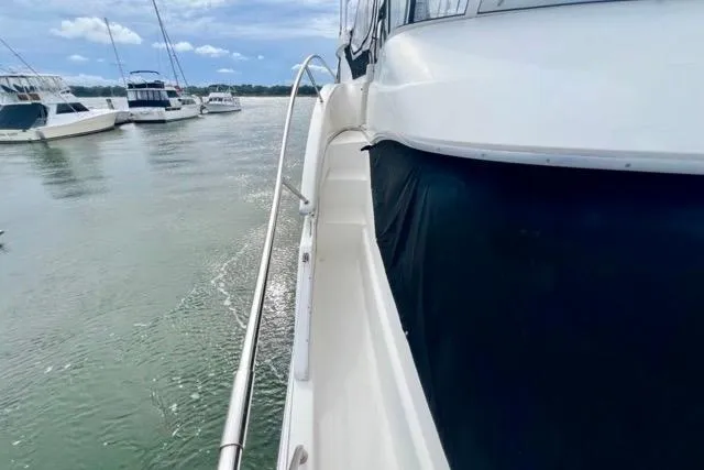 Slide: The Image of 2003 Silverton 43 Motor Yacht on calm waters, docked alongside other boats. - 21