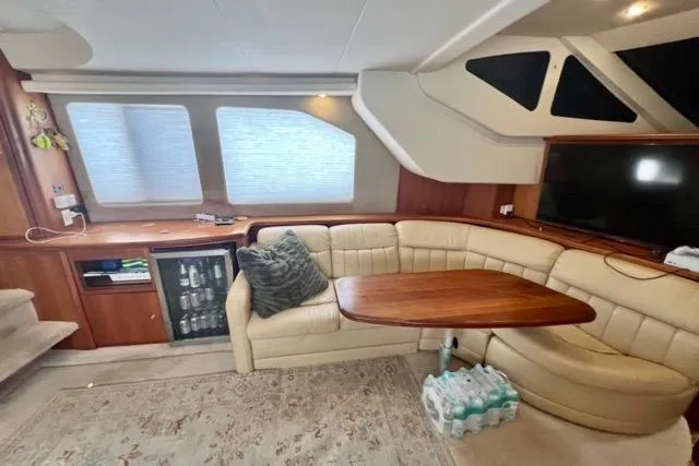 Slide: The Image of Interior of 2003 Silverton 43 Motor Yacht with beige seating, wooden table, and large windows. - 24