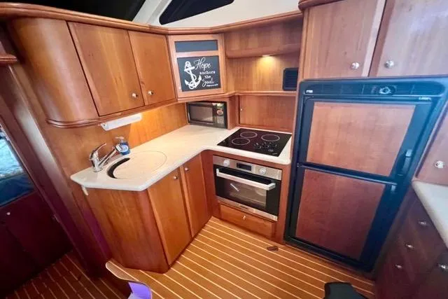 Slide: The Image of 2003 Silverton 43 Motor Yacht kitchen with wood cabinetry, stove, oven, and refrigerator. - 26