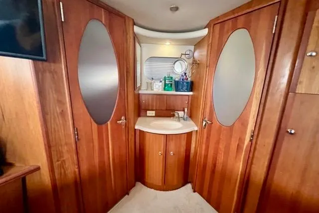 Slide: The Image of Interior of 2003 Silverton 43 Motor Yacht bathroom with wooden cabinetry and oval mirrors. - 37