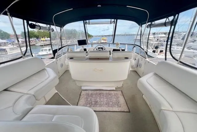 Slide: The Image of 2003 Silverton 43 Motor Yacht interior with white seating and helm, overlooking marina. - 7